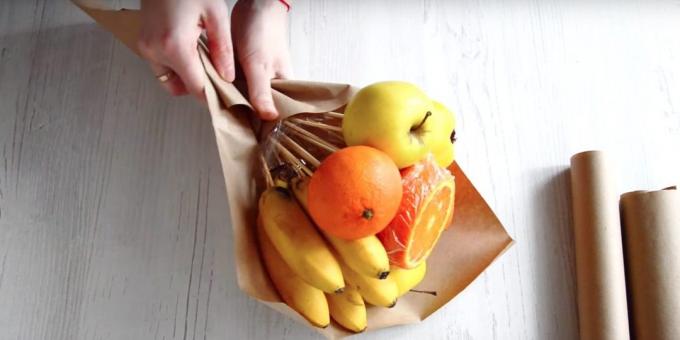 Mettere un po 'di frutta con le mani diagonalmente attraverso la carta e avvolgere il fondo